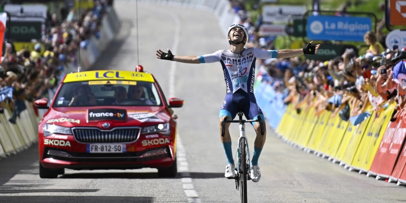 Photo from finishline where Martinez makes a victory sign putting his hands up wiht an extatic crown in the background